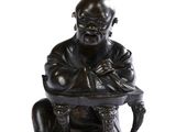 une photo représentant la statue d'un homme assis sur un tabouret