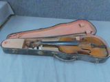 un violon dans son étui, posé sur un lit