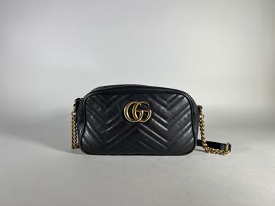 a black gucci bag with a gold gg logo on the front