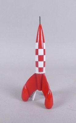 une petite fusée jouet rouge et blanche posée sur une surface blanche