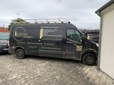 une camionnette noire garée sur un parking à côté d'un immeuble