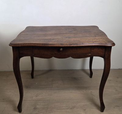 une vieille table en bois avec un tiroir en dessous, posée sur un parquet en bois massif