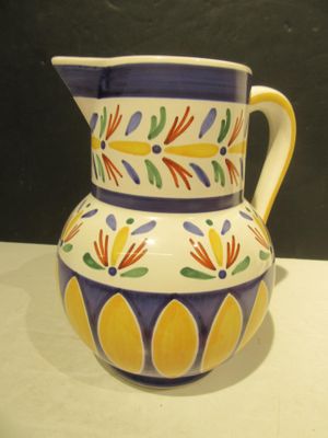 a colorful pitcher sitting on a table with a black wall in the background