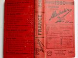 an old red book sitting on top of a table next to a white table