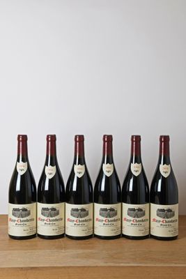 six bouteilles de vin rouge alignées sur une table en bois