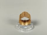 un gros plan d'une bague en or posée sur un socle transparent
