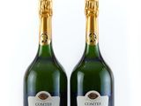 two bottles of champagne sitting next to each other on a white surface