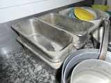 Plusieurs casseroles sont alignées sur un plan de travail dans une cuisine