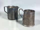 two silverplated mugs with handles on a white surface