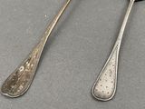 two spoons and a fork on a table next to each other