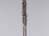 a silver and black clarinet sitting on top of a clear stand