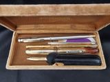 quatre stylos dans une boîte posée sur un tissu noir