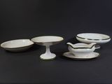 four pieces of white and green china on a black table