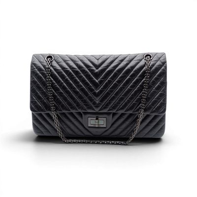 a black quilted bag with a chain strap on a white background