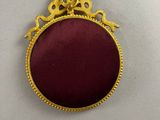 a close up of a red and gold broochle on a white surface