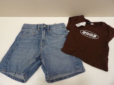 une chemise marron et un short bleu posés sur une table blanche