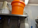 an orange bucket sitting on top of a shelf next to a toilet