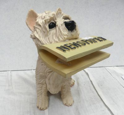 statue of a dog with a book in its mouth sitting on a table