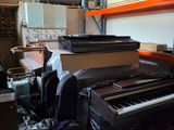 a piano in a room with a lot of clutter on the floor
