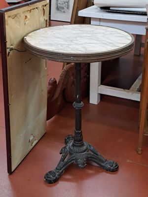 une petite table au plateau en marbre posée sur un sol rouge