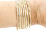 three gold and silver bang bracelets on a woman ' s arm