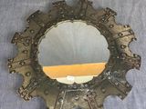 un vieux miroir avec un cadre en métal et quelques ornements métalliques