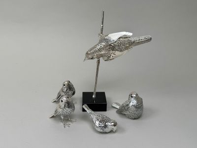 une statue en argent représentant un oiseau et trois oiseaux