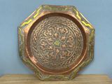 brass plate on wooden table with blue wall in background
