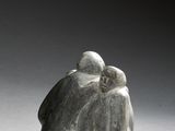 sculpture of a couple sitting on a rock on a gray surface