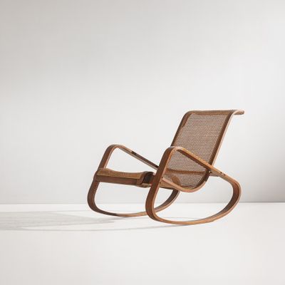 un fauteuil à bascule en bois avec une assise en osier, posé sur une surface blanche