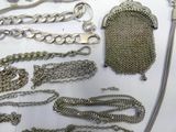 a lot of silver chains and a purse on a table