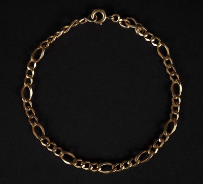 gros plan d'un bracelet en chaîne en or sur fond noir
