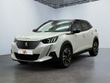 La voiture blanche est garée dans une grande pièce aux murs blancs.