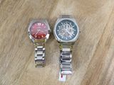 two watches sitting on a wooden table next to each other