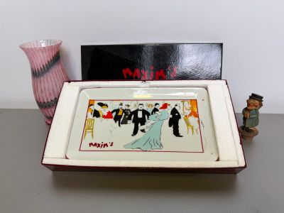 a small tray with a painting on it next to a vase