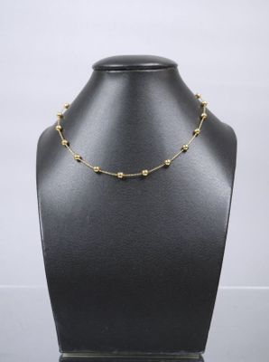 a black mannequin with a gold bead necklace on it