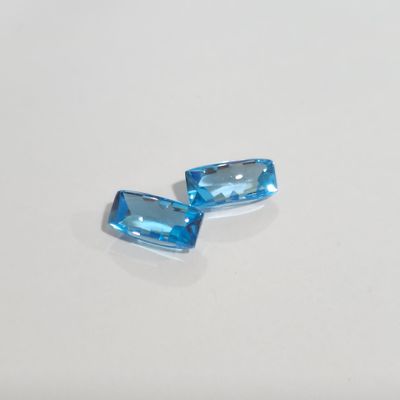 a pair of blue topazte gems on a white surface