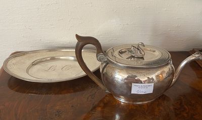 a silver tea pot on a wooden table with a silver plate