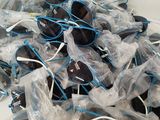 many pairs of sunglasses wrapped in plastic bags on a table