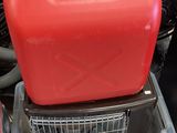un bidon d'essence rouge posé sur un récipient en plastique