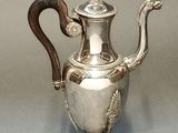 an antique silver teapot with a wooden handle on a stand