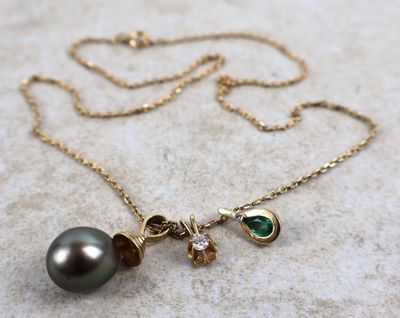 un gros plan d'un collier orné d'une perle noire et d'une pierre verte