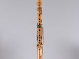 a clarinet with a wooden body and a black top on a clear stand