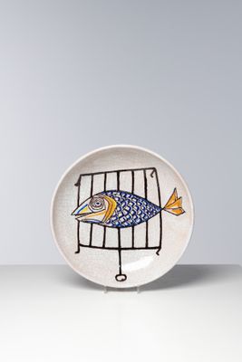 une petite assiette sur laquelle est posé un poisson, posée sur une table