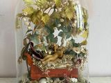 une cloche en verre posée sur une table, avec une figurine à l'intérieur