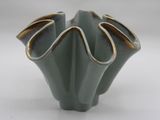a green vase with a gold rim sitting on a white surface