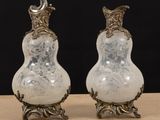 pair of silver and white glass vases sitting on top of a wooden table