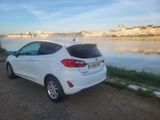 the rear end of a white car parked next to a body of water