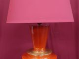une lampe de table orange surmontée d'un abat-jour rose