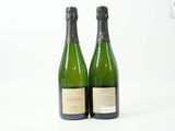 deux bouteilles de champagne posées l'une à côté de l'autre sur une surface blanche